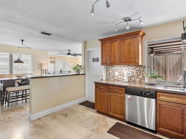 kitchen featuring a textured ceiling, stainless steel dishwasher, a healthy amount of sunlight, and sink