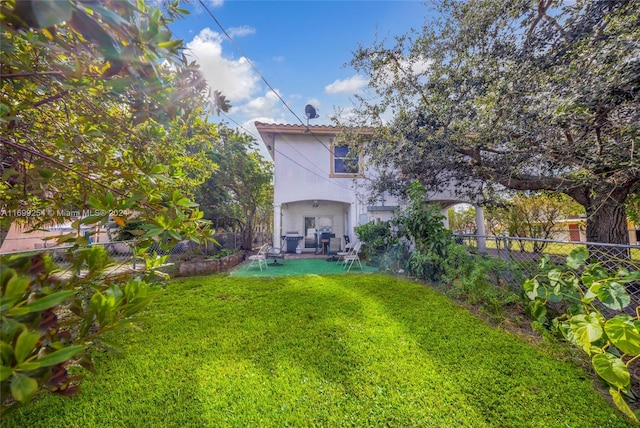 rear view of house featuring a lawn and a patio