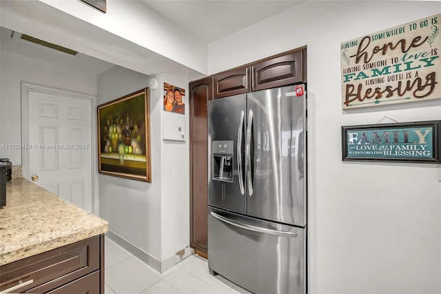 kitchen with dark brown cabinetry, stainless steel fridge, and light tile patterned floors