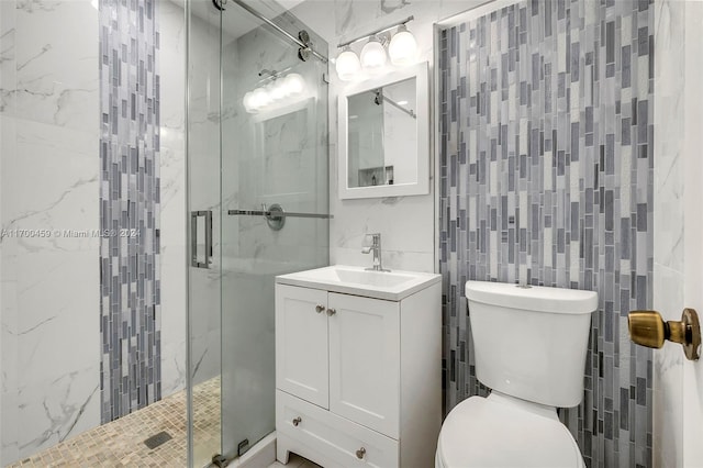 bathroom featuring a shower with door, vanity, tile walls, and toilet