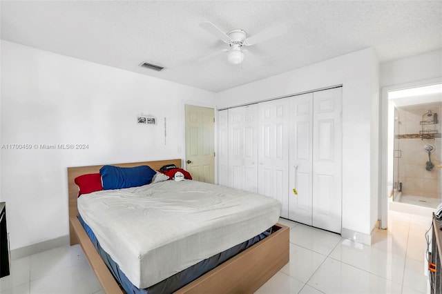 tiled bedroom with ceiling fan, a textured ceiling, and a closet