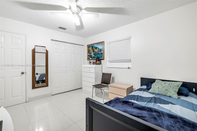 tiled bedroom featuring ceiling fan, a textured ceiling, and a closet