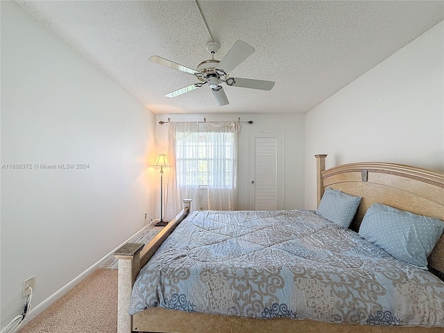 bedroom featuring ceiling fan, carpet floors, and a textured ceiling