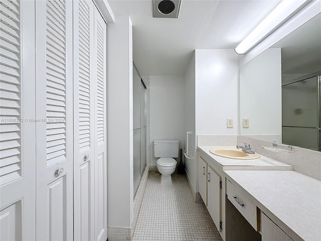 bathroom with tile patterned floors, vanity, toilet, and walk in shower