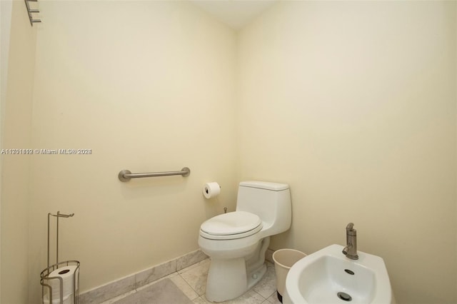 bathroom featuring tile patterned flooring, toilet, and a bidet