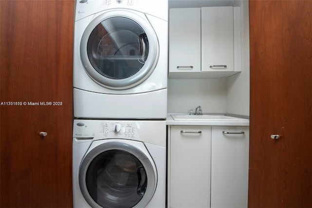 laundry room with cabinets, sink, and stacked washer and clothes dryer