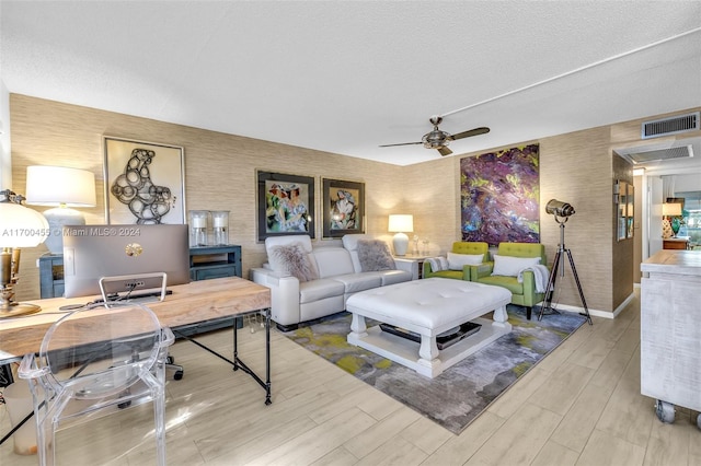 living room featuring ceiling fan, a textured ceiling, and light wood-type flooring