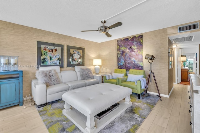 living room featuring ceiling fan, a textured ceiling, and light hardwood / wood-style flooring