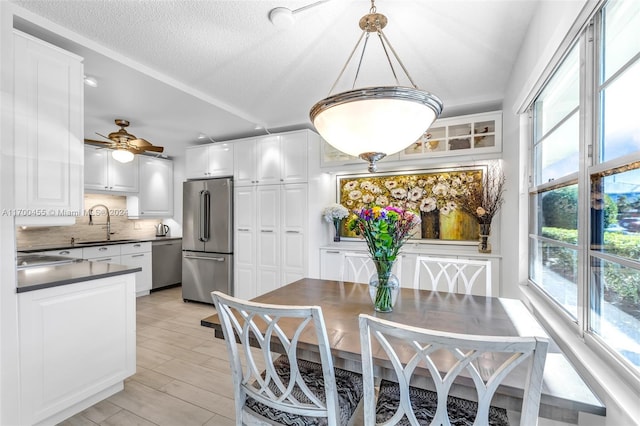 dining area with a wealth of natural light, sink, ceiling fan, and a textured ceiling