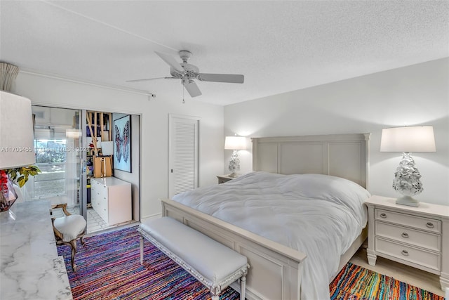 bedroom featuring ceiling fan, a closet, light hardwood / wood-style floors, and a textured ceiling