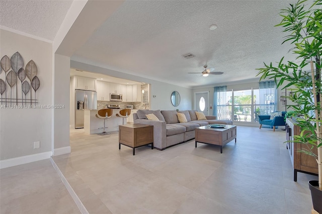 living room featuring ceiling fan, ornamental molding, and a textured ceiling