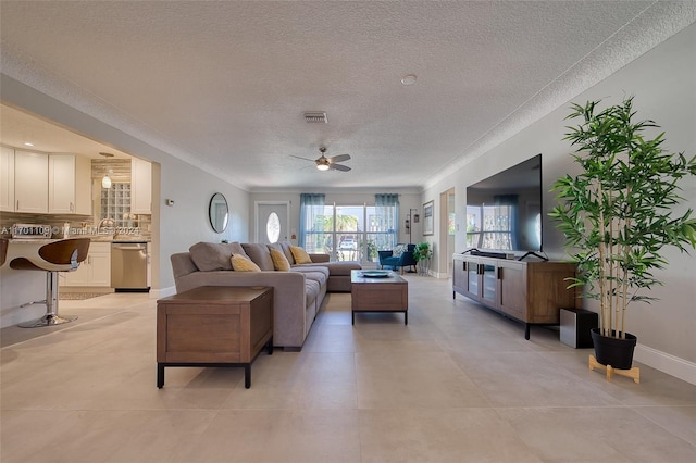 living room with ceiling fan, sink, and a textured ceiling