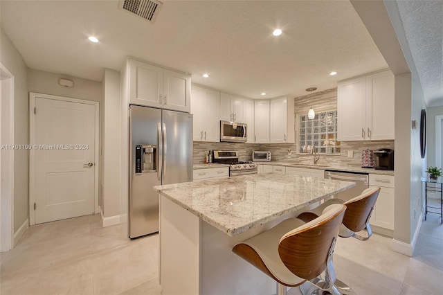 kitchen with a center island, white cabinetry, backsplash, and appliances with stainless steel finishes