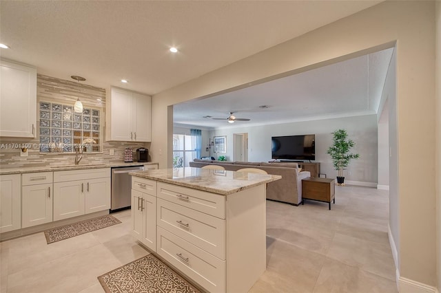 kitchen featuring light stone countertops, decorative backsplash, white cabinetry, and stainless steel dishwasher