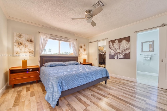 bedroom with a spacious closet, ceiling fan, light hardwood / wood-style floors, a textured ceiling, and a closet