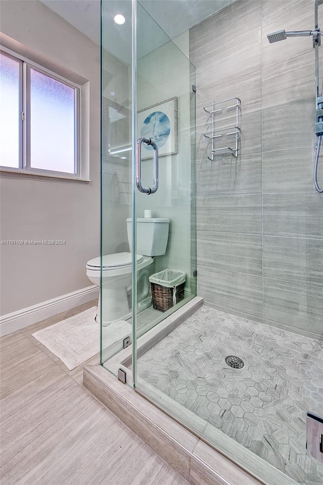 bathroom featuring hardwood / wood-style floors, a shower with door, and toilet