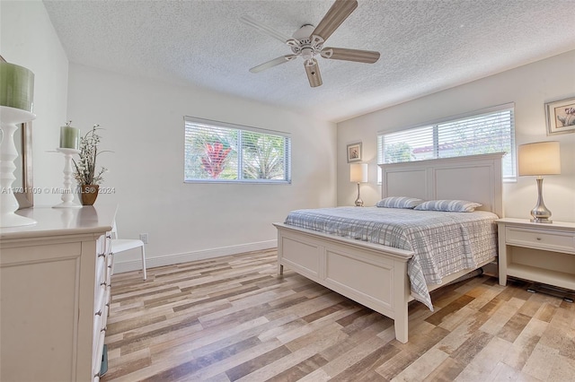 bedroom featuring ceiling fan, light hardwood / wood-style floors, and a textured ceiling