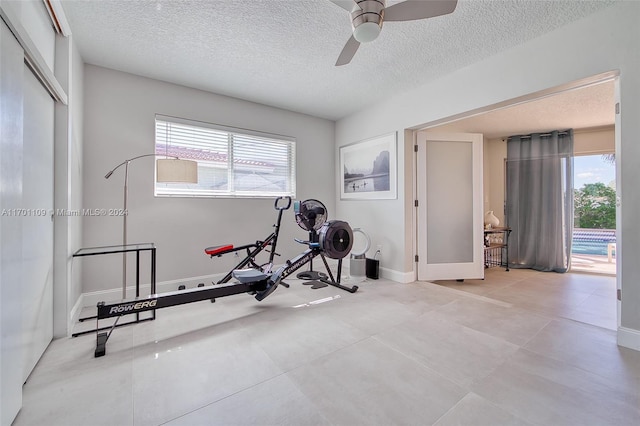 workout area featuring ceiling fan, plenty of natural light, and a textured ceiling