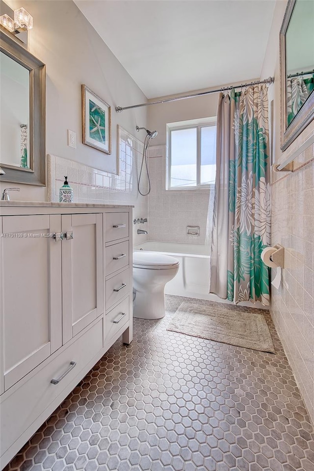 full bathroom featuring shower / tub combo with curtain, vanity, tile walls, and toilet