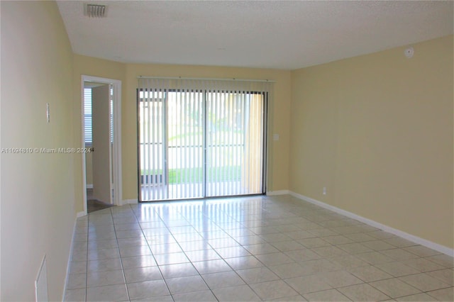 empty room with light tile patterned floors and a textured ceiling