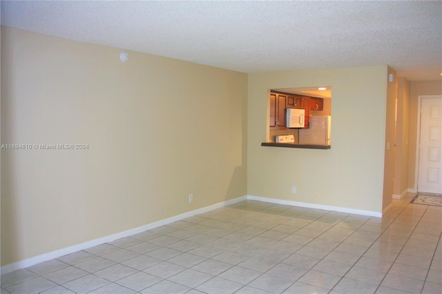 tiled empty room with a textured ceiling