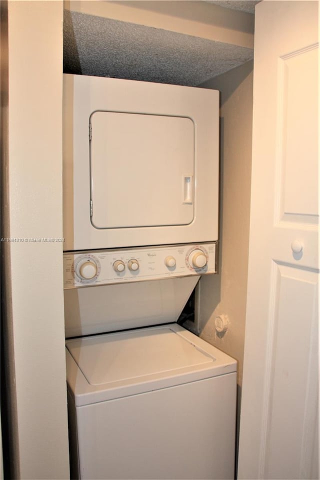 washroom featuring a textured ceiling and stacked washing maching and dryer