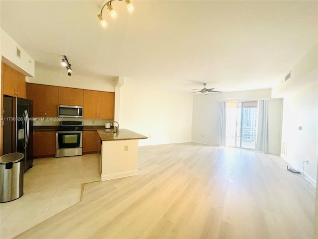 kitchen featuring ceiling fan, kitchen peninsula, sink, light wood-type flooring, and appliances with stainless steel finishes