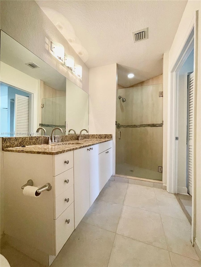 bathroom featuring a shower with shower door, a textured ceiling, and vanity