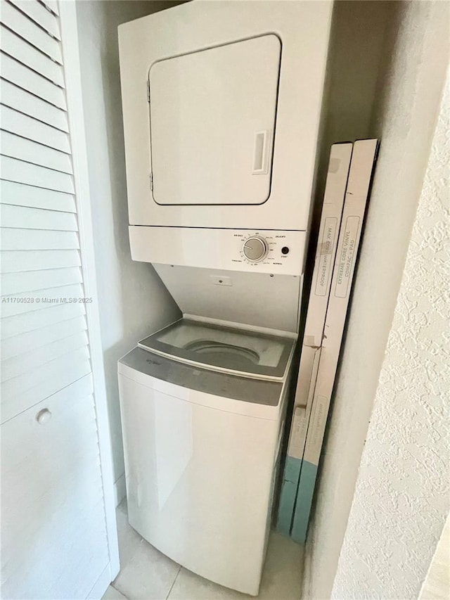 laundry area featuring stacked washer and clothes dryer and light tile patterned flooring