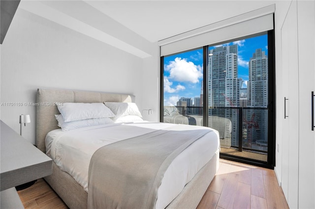 bedroom featuring access to exterior, light hardwood / wood-style floors, and floor to ceiling windows