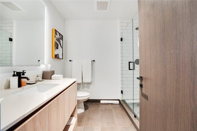 bathroom featuring tile patterned flooring, an enclosed shower, vanity, and toilet