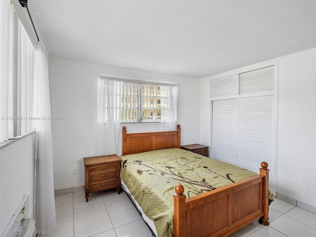 bedroom with light tile patterned floors, a textured ceiling, and a closet