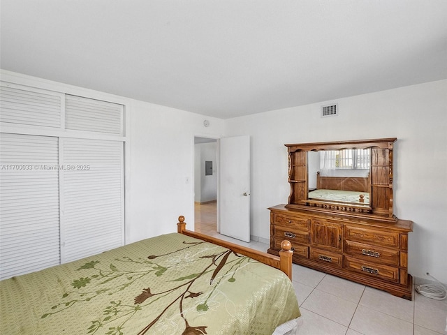 bedroom with visible vents, light tile patterned floors, and a closet