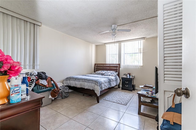 tiled bedroom with ceiling fan and a textured ceiling