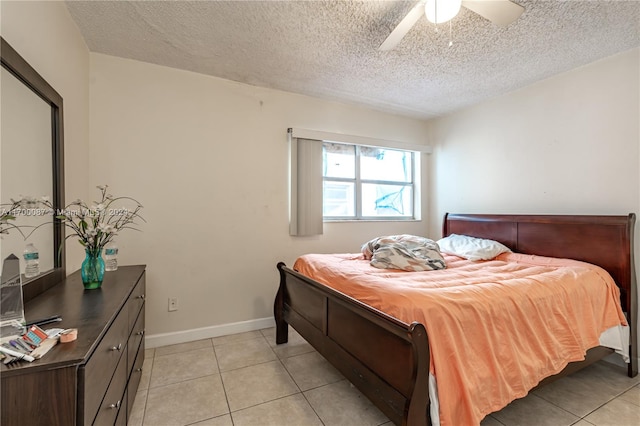 bedroom with ceiling fan, light tile patterned floors, and a textured ceiling