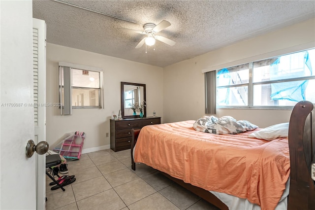 bedroom featuring ceiling fan, light tile patterned floors, and a textured ceiling