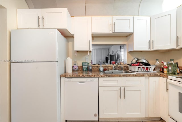 kitchen with sink, white cabinets, dark stone counters, and white appliances