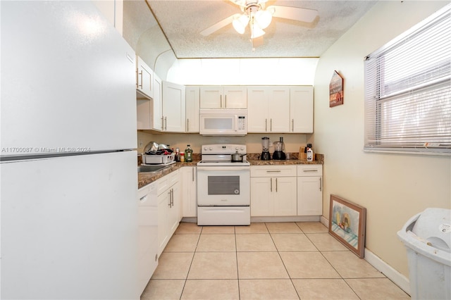 kitchen featuring ceiling fan, dark stone countertops, a textured ceiling, white appliances, and light tile patterned floors