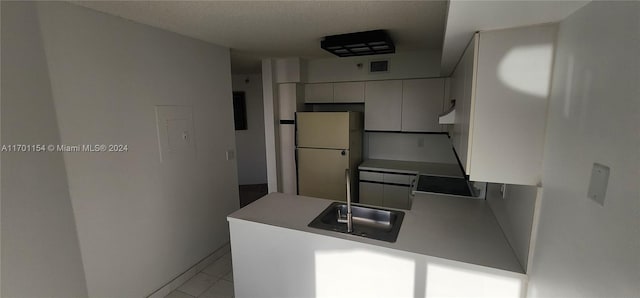 kitchen featuring white cabinets, white refrigerator, sink, cooktop, and kitchen peninsula