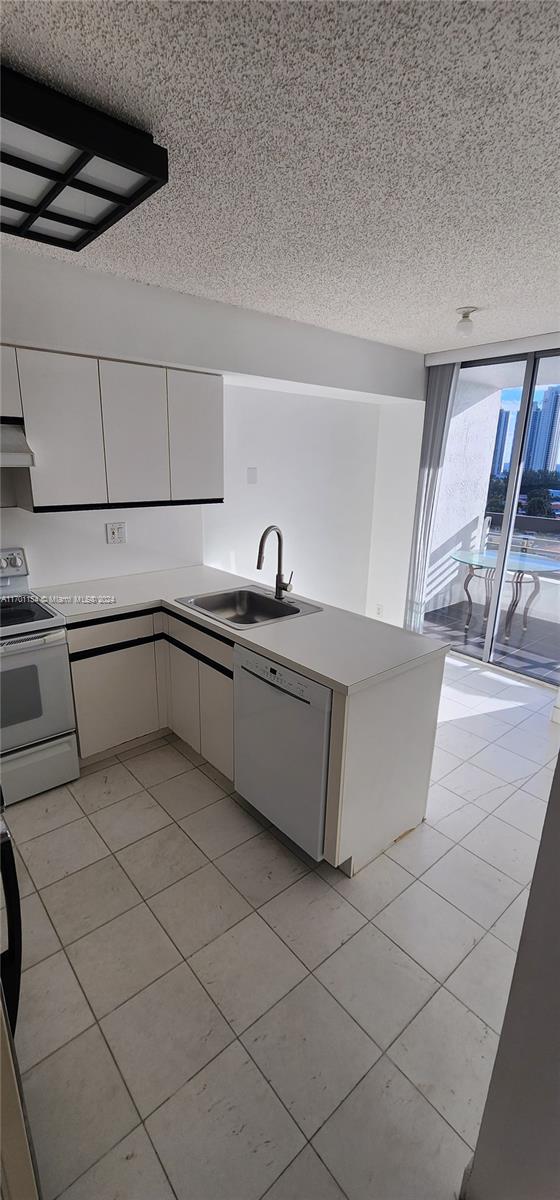 kitchen featuring kitchen peninsula, a textured ceiling, white appliances, and sink