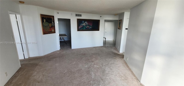 hall featuring a textured ceiling and light colored carpet