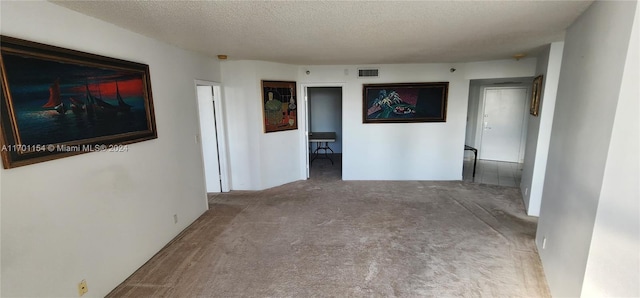 hallway with carpet flooring and a textured ceiling