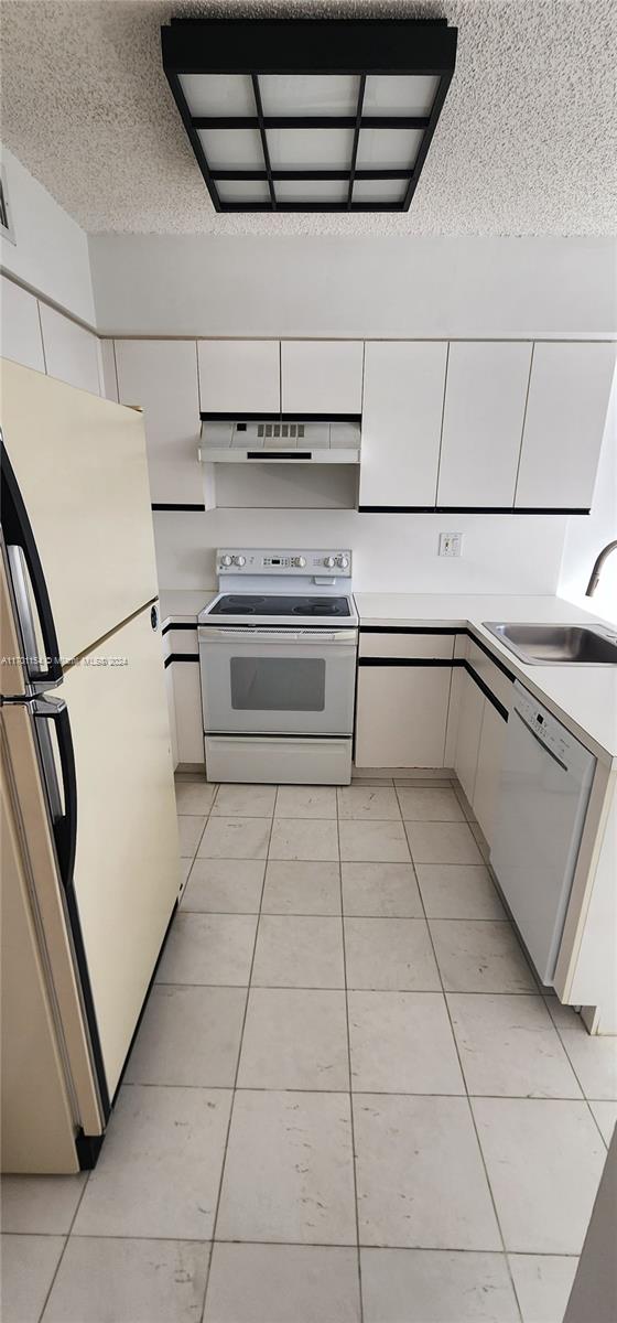 kitchen with a textured ceiling, white cabinets, white appliances, and sink