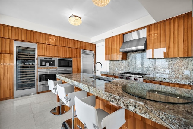 kitchen featuring sink, wall chimney exhaust hood, tasteful backsplash, wine cooler, and built in appliances