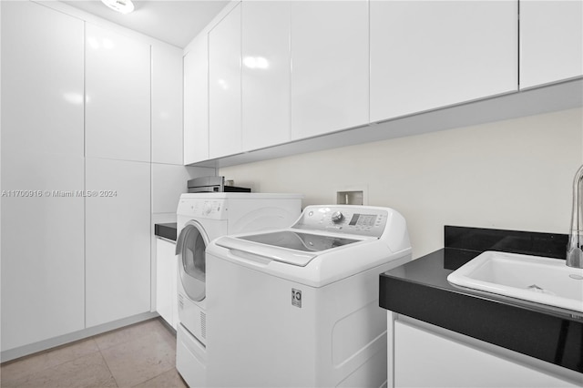 clothes washing area with washer and dryer, cabinets, light tile patterned floors, and sink