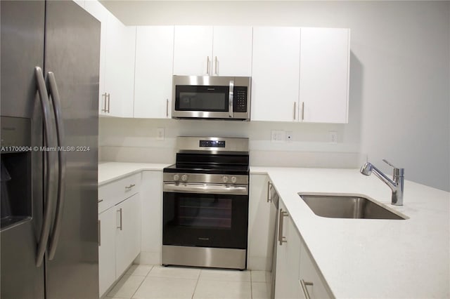 kitchen featuring white cabinetry, sink, light tile patterned floors, and appliances with stainless steel finishes