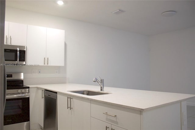 kitchen with kitchen peninsula, sink, white cabinets, and appliances with stainless steel finishes