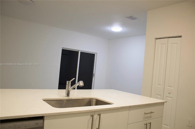 kitchen with dishwashing machine, white cabinetry, and sink