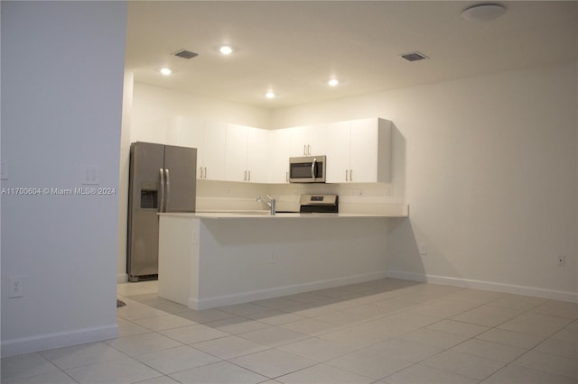 kitchen featuring white cabinets, kitchen peninsula, stainless steel appliances, and light tile patterned floors