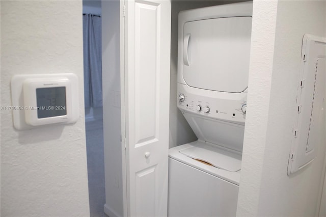 clothes washing area featuring stacked washer / dryer and electric panel